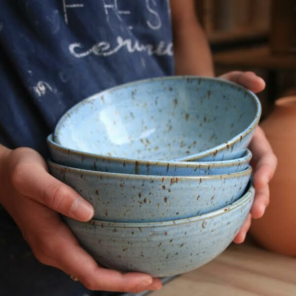 the woman holds handmade ceramic bowls in her hands